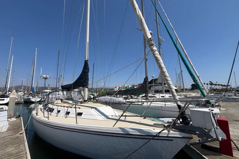 1987 Catalina 34 sailboat docked at marina under clear blue sky.