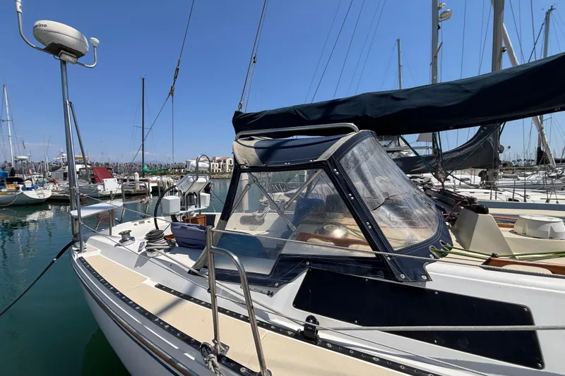 1987 Catalina 34 sailboat docked in marina, featuring a covered cockpit and clear skies.