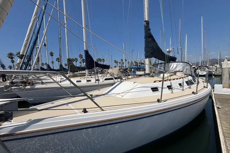 1987 Catalina 34 sailboat docked at marina under clear blue sky.