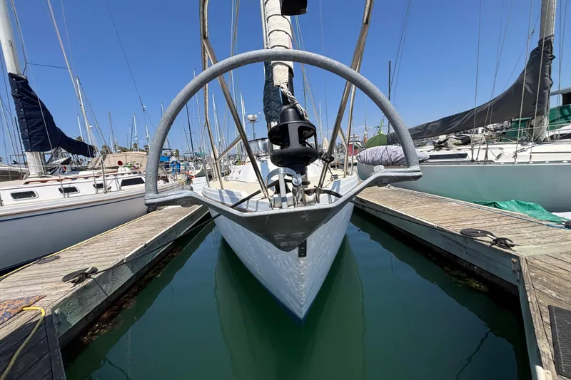 1987 Catalina 34 sailboat docked in marina, viewed from bow, surrounded by other boats.