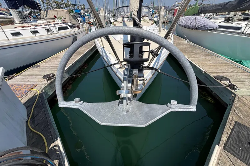 1987 Catalina 34 sailboat docked, featuring a prominent steering wheel and marina surroundings.