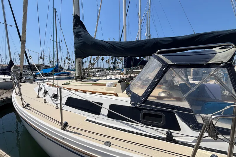 1987 Catalina 34 sailboat docked in a marina under clear blue skies.
