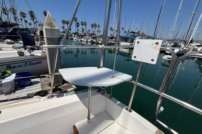1987 Catalina 34 sailboat docked in marina, surrounded by other boats and palm trees.