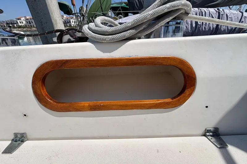 Wooden handrail on a 1987 Catalina 34 sailboat deck, with coiled rope nearby.