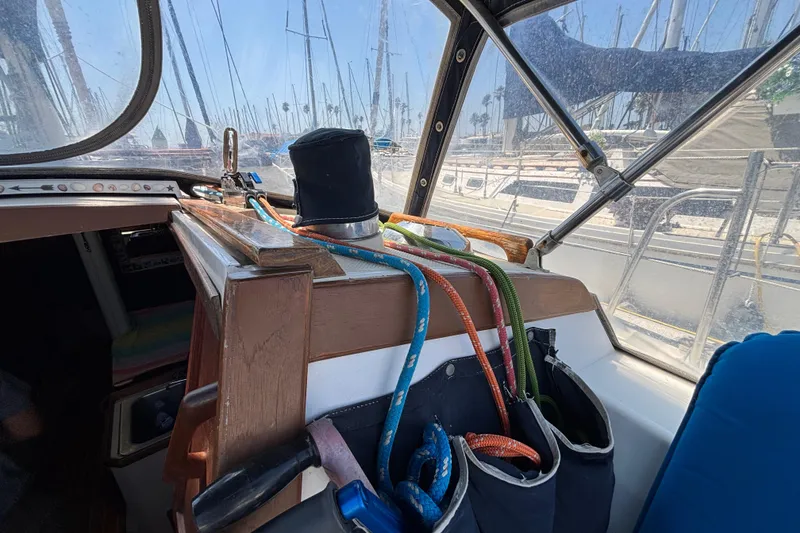 Interior view of a 1987 Catalina 34 sailboat cockpit with ropes and marina background.