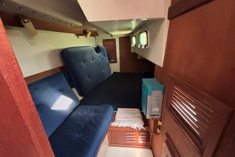 Interior cabin of a 1987 Catalina 34 sailboat with blue upholstery and wooden accents.