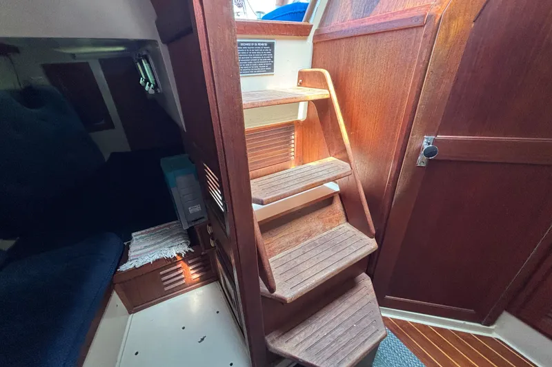 Interior of 1987 Catalina 34 sailboat with wooden steps and cozy cabin area.