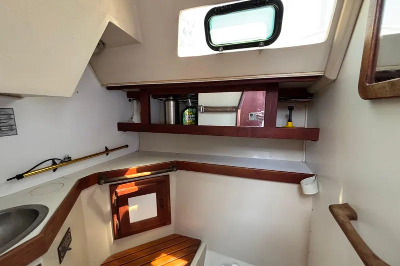 Interior of 1987 Catalina 34 sailboat with wooden shelves and porthole window.