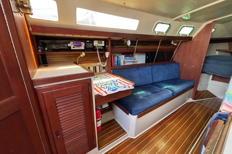 Interior of 1987 Catalina 34 sailboat with blue seating and wooden cabinetry.