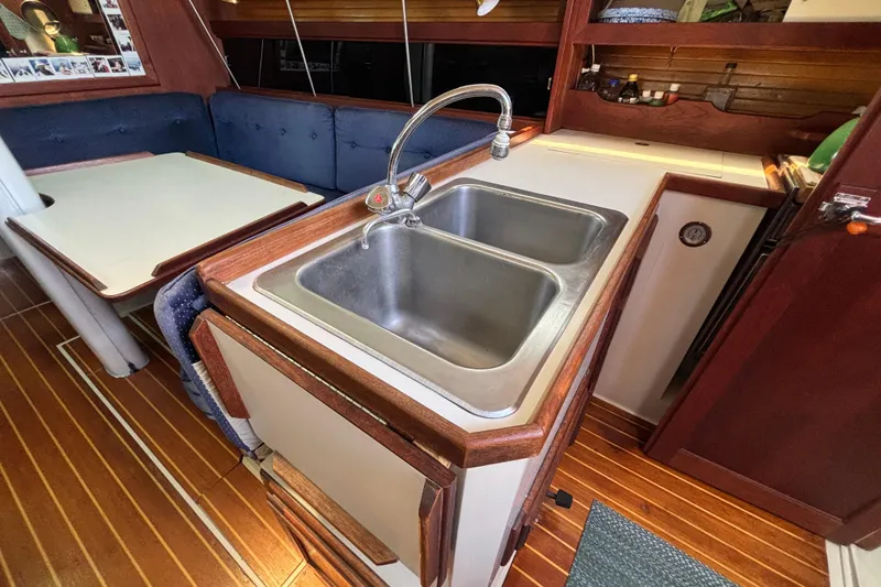 Interior of a 1987 Catalina 34 sailboat featuring a kitchen sink and dining area.