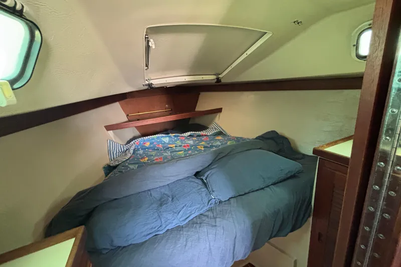 Cozy cabin interior of 1987 Catalina 34 sailboat with comfortable bedding and wooden accents.