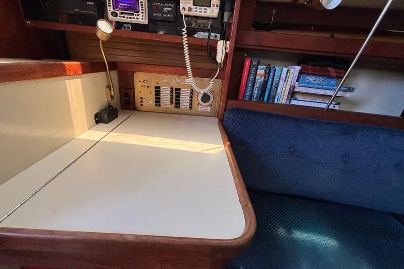 Navigation station inside a 1987 Catalina 34 sailboat with books and communication equipment.