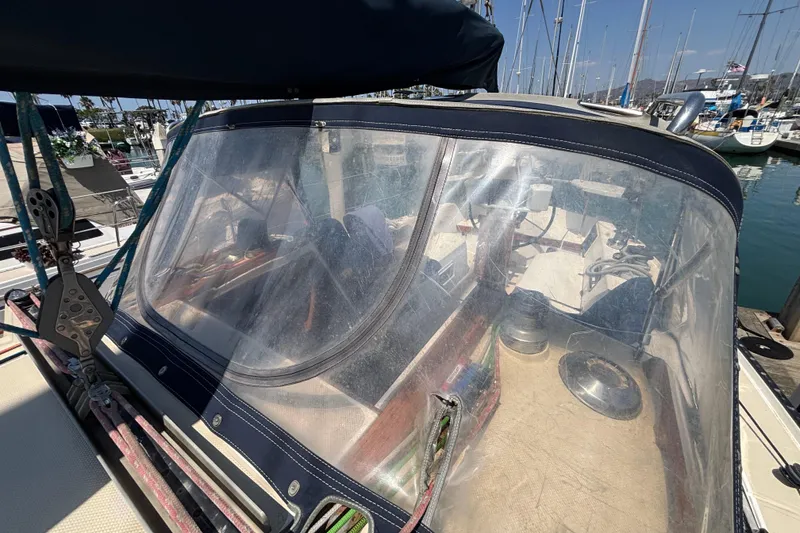 1987 Catalina 34 sailboat cockpit with clear protective cover in marina setting.