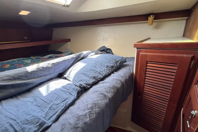 Cozy cabin interior of 1987 Catalina 34 sailboat with bed and wooden cabinet.