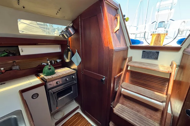 Interior of 1987 Catalina 34 sailboat with wooden cabinetry and compact kitchen area.