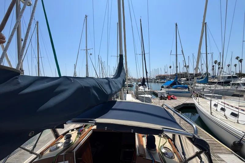 Sailboat docked in marina, Catalina 34 model, 1987, surrounded by other boats under clear sky.