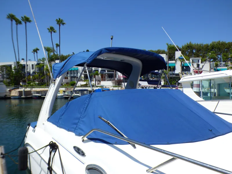 2003 Sea Ray 260 Sundancer boat with blue cover docked in marina.