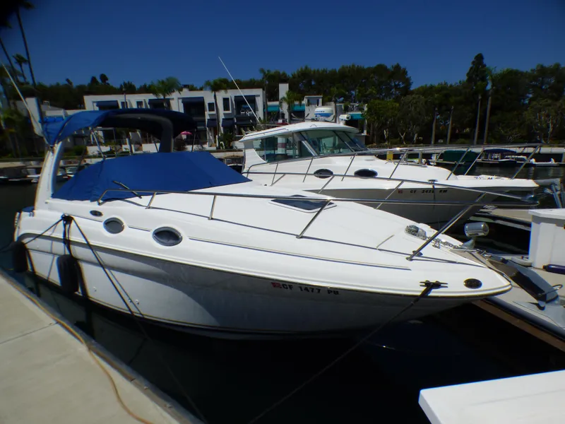 2003 Sea Ray 260 Sundancer boat docked at marina under clear blue sky.