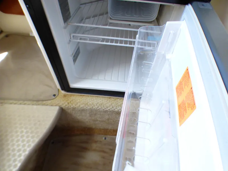 Open fridge inside 2003 Sea Ray 260 Sundancer boat, showing interior shelves.