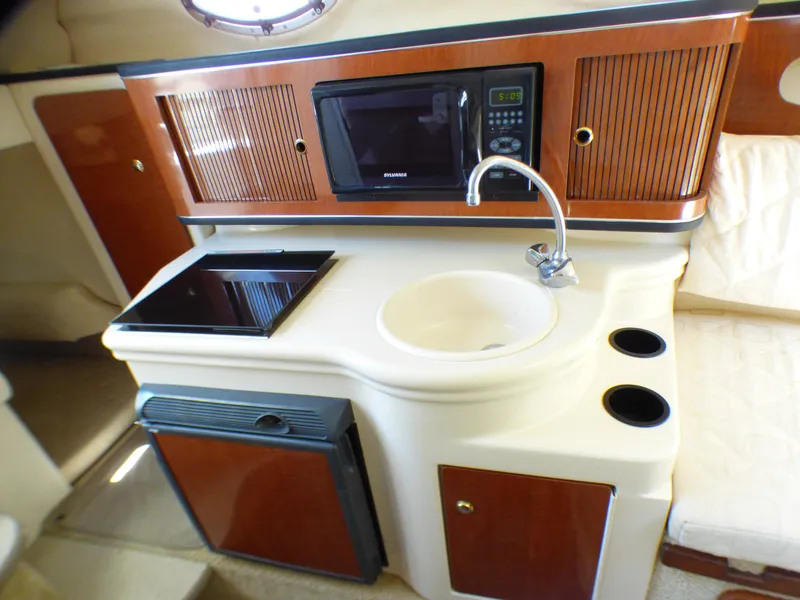2003 Sea Ray 260 Sundancer cabin kitchen with sink, microwave, and stove.