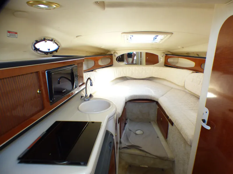 2003 Sea Ray 260 Sundancer cabin interior with kitchenette, sink, and cozy sleeping area.