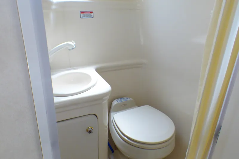 Compact bathroom in 2003 Sea Ray 260 Sundancer boat with sink and toilet.