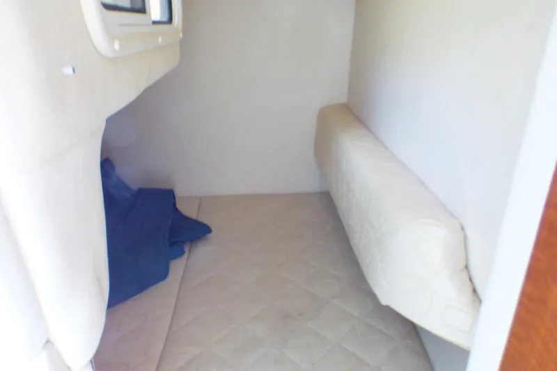 2003 Sea Ray 260 Sundancer cabin interior with beige upholstery and compact sleeping area.