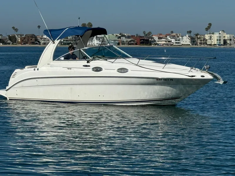 2003 Sea Ray 260 Sundancer boat on calm water with coastal background.