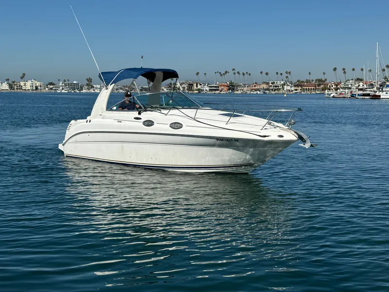 2003 Sea Ray 260 Sundancer boat cruising on calm waters under a clear blue sky.