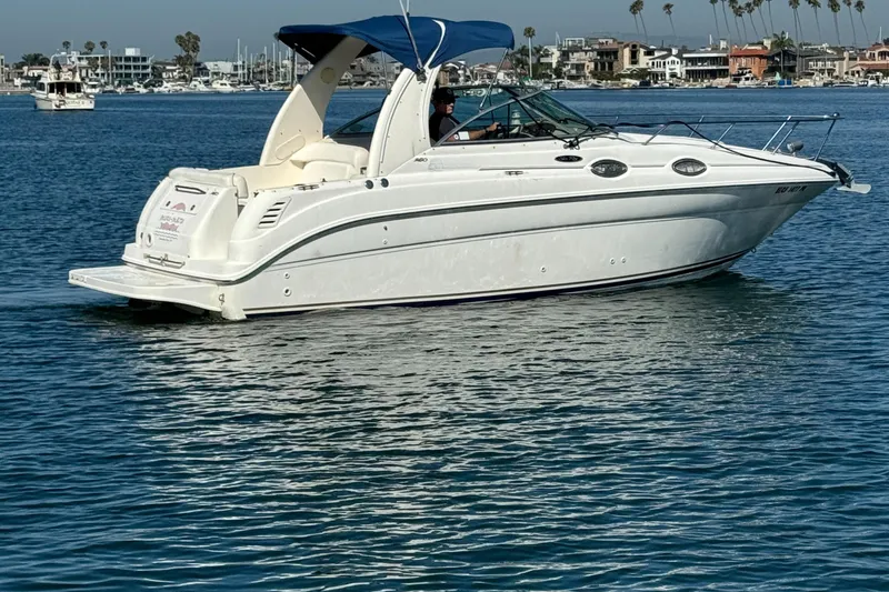 2003 Sea Ray 260 Sundancer boat cruising on calm blue water.