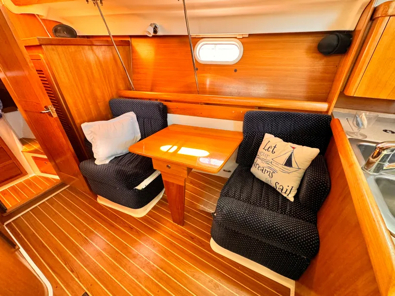 Interior of 2004 Catalina 350 sailboat with cozy seating and wooden table.