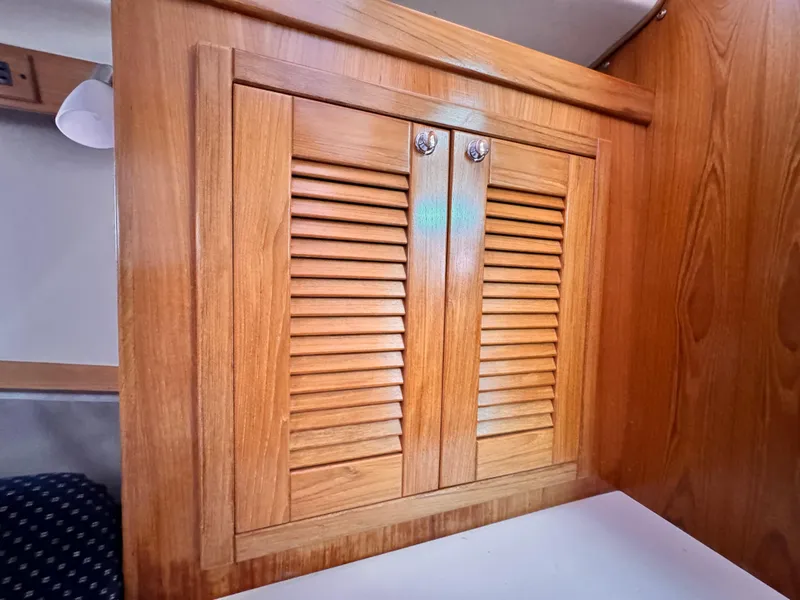 Wooden cabinet with louvered doors inside a 2004 Catalina 350 sailboat.