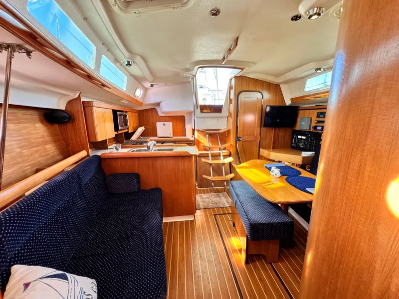 Interior of a 2004 Catalina 350 sailboat with wood finish and cozy seating area.