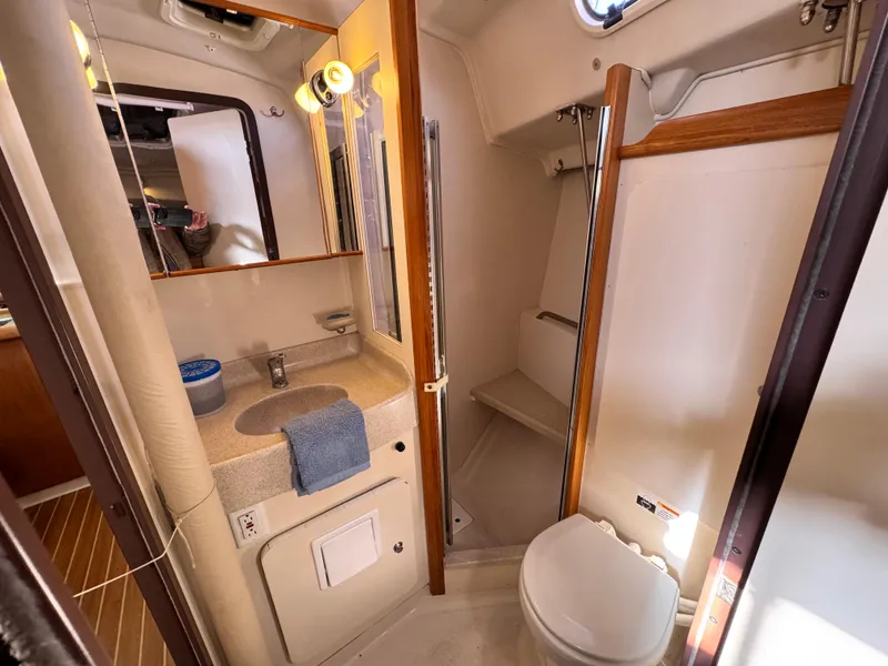Bathroom interior of a 2004 Catalina 350 yacht, featuring sink, toilet, and shower.