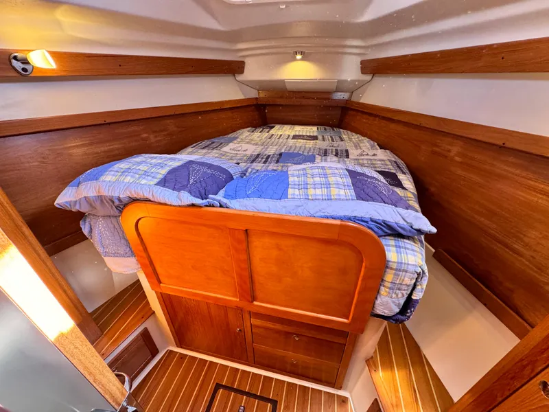 Cozy cabin interior of 2004 Catalina 350 sailboat with wooden finish and bed.