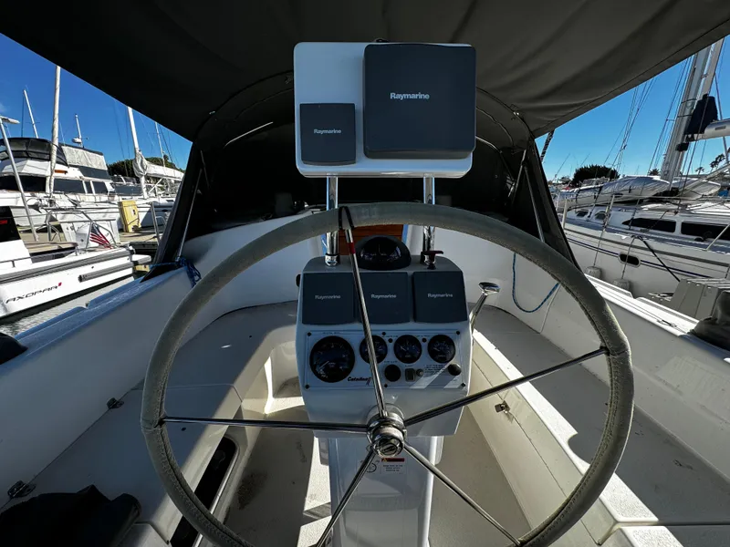 Steering wheel and controls of a 2004 Catalina 350 sailboat in a marina.
