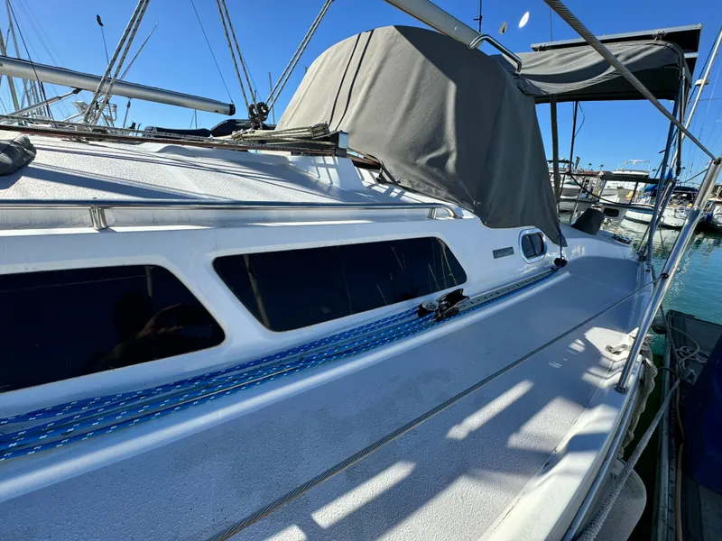2004 Catalina 350 sailboat with covered cockpit, docked in marina under clear blue sky.
