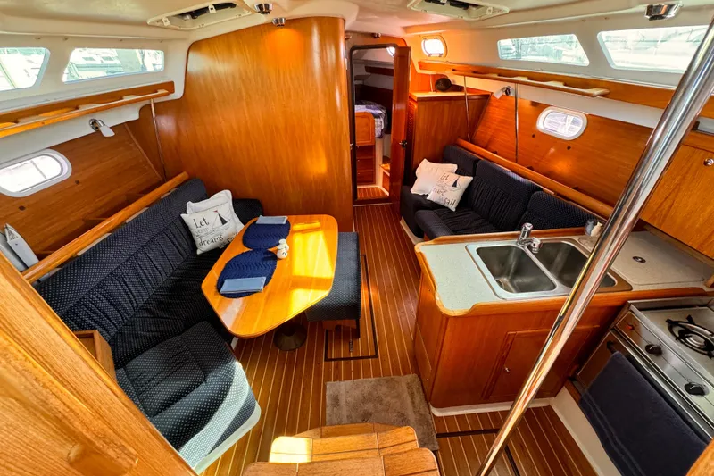 Interior of a 2004 Catalina 350 sailboat with wood finish and cozy seating area.