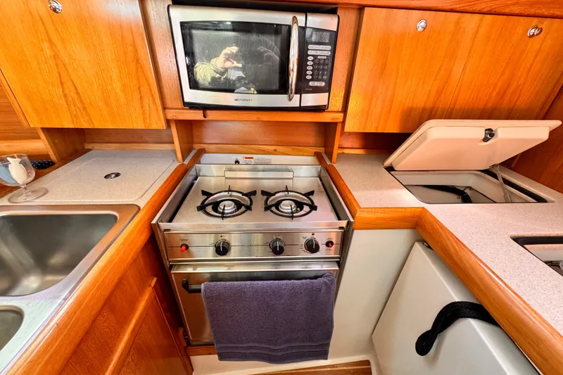 Compact kitchen in a 2004 Catalina 350 yacht with stove, microwave, and sink.