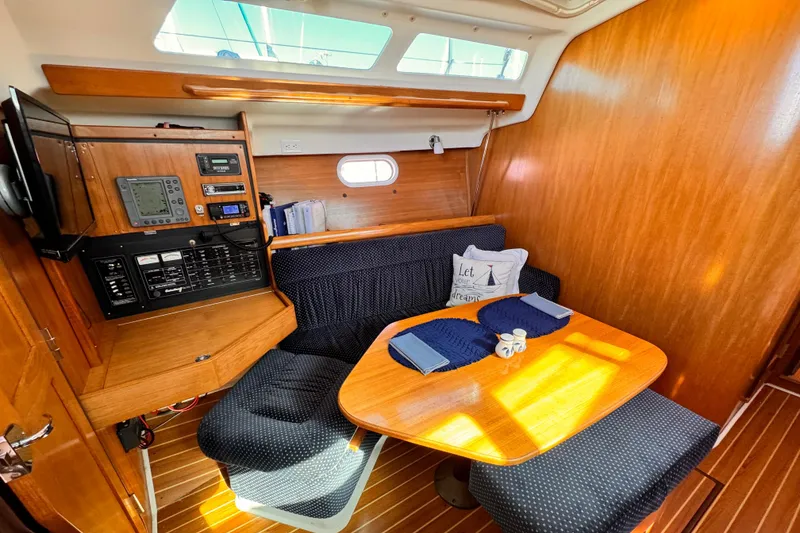 Cozy interior of 2004 Catalina 350 sailboat with dining area and navigation equipment.
