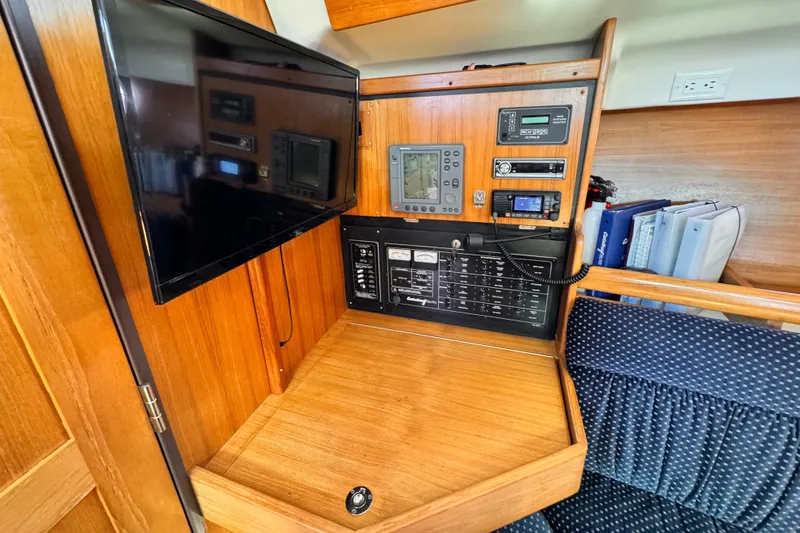Navigation station in a 2004 Catalina 350 sailboat with control panels and a mounted screen.