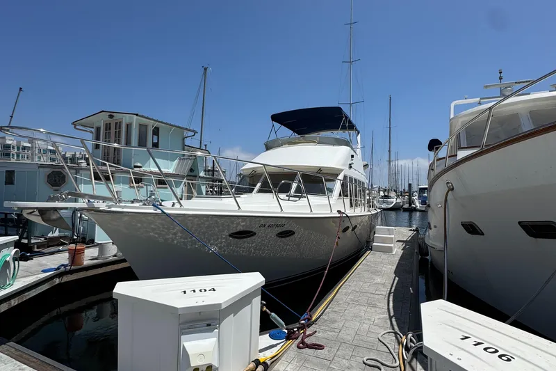 1999 McKinna 47 Sedan yacht docked at marina under clear blue sky.