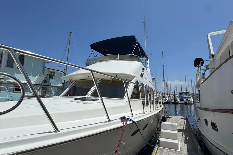 1999 McKinna 47 Sedan yacht docked at marina under clear blue sky.