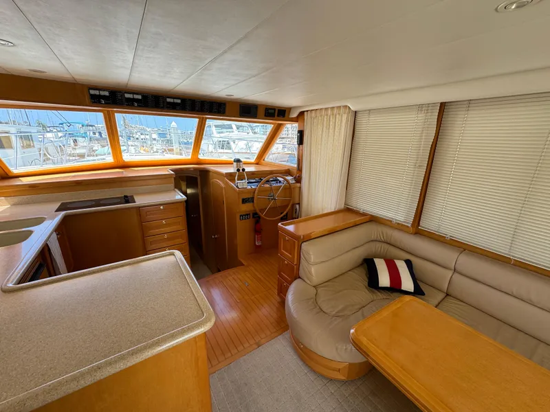 Interior of a 1999 McKinna 47 Sedan yacht with helm, seating, and windows.