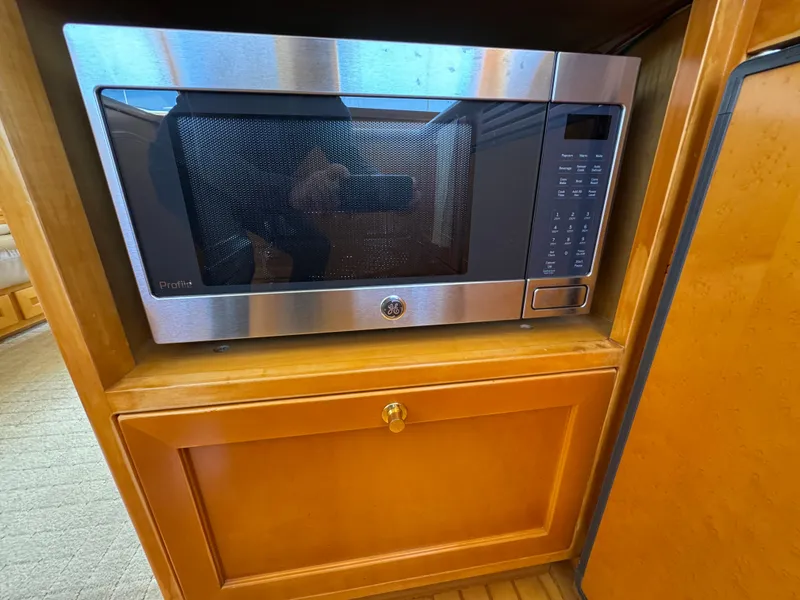 Microwave in wooden cabinet on 1999 McKinna 47 Sedan yacht interior.