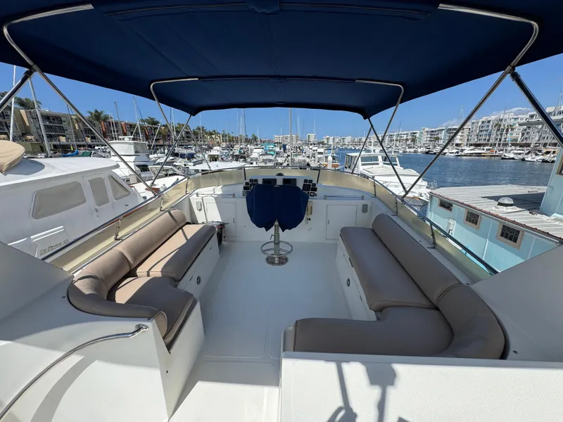 1999 McKinna 47 Sedan yacht with spacious seating and blue canopy in a marina.