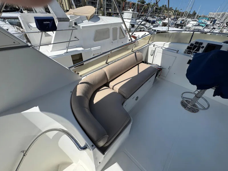 1999 McKinna 47 Sedan yacht with cushioned seating on deck, docked at marina.