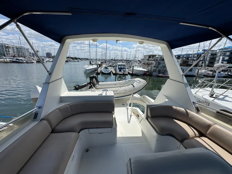 1999 McKinna 47 Sedan yacht interior with marina view, featuring comfortable seating and a dinghy.