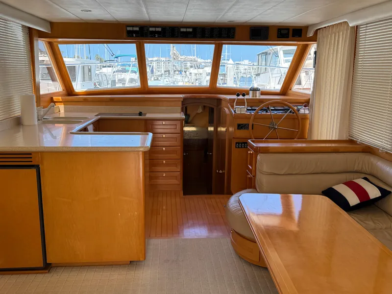 Interior of 1999 McKinna 47 Sedan yacht with wooden finishes and large windows.