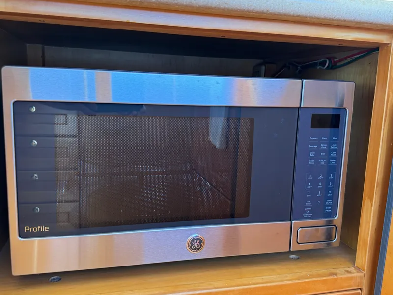 Stainless steel GE Profile microwave in a wooden cabinet on a 1999 McKinna 47 Sedan.